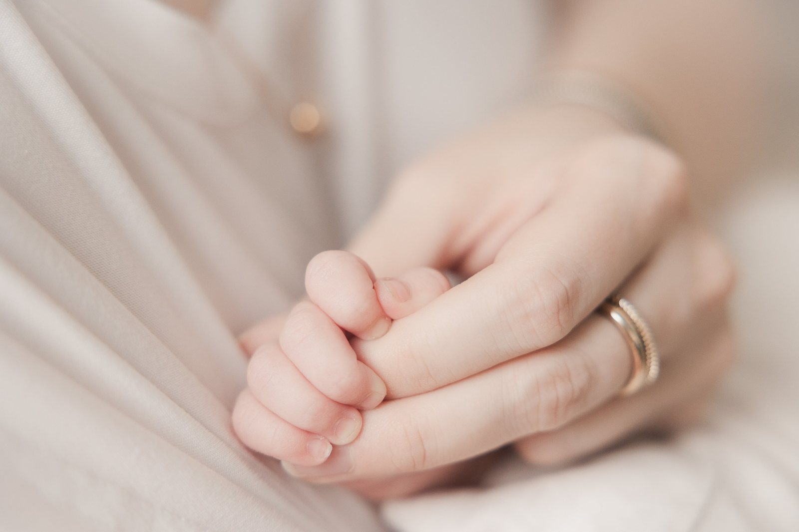 Babyhand umschließt den Finger der Mama