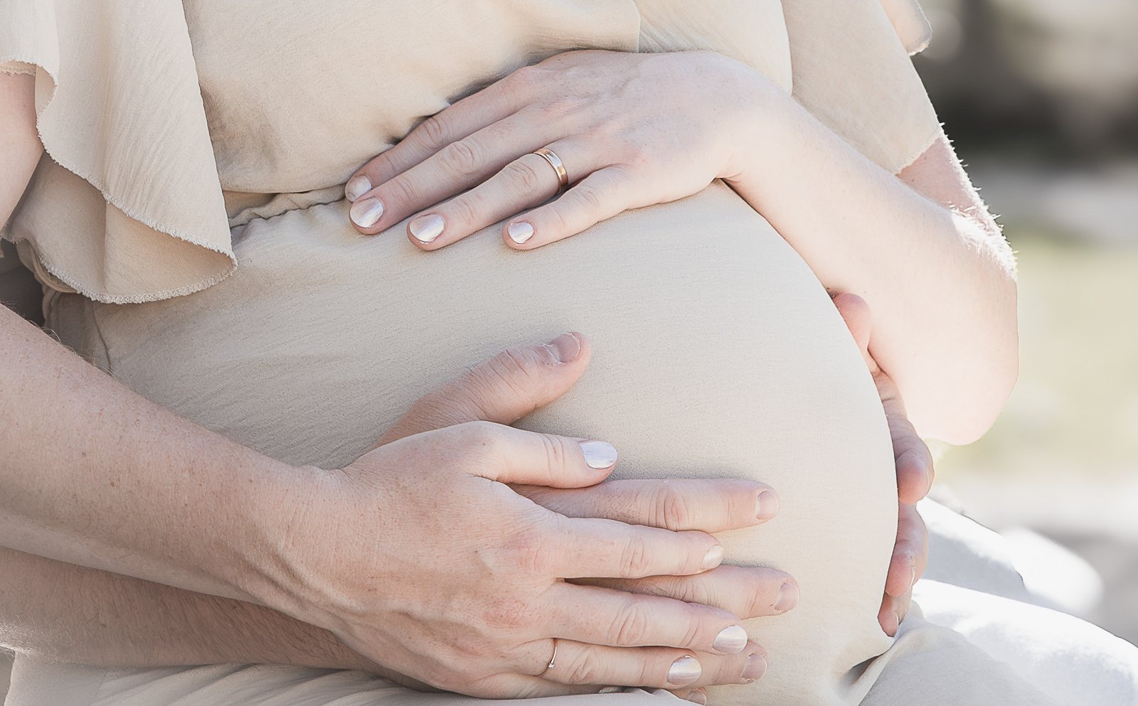 Hände der werdenden Eltern auf dem Babybauch
